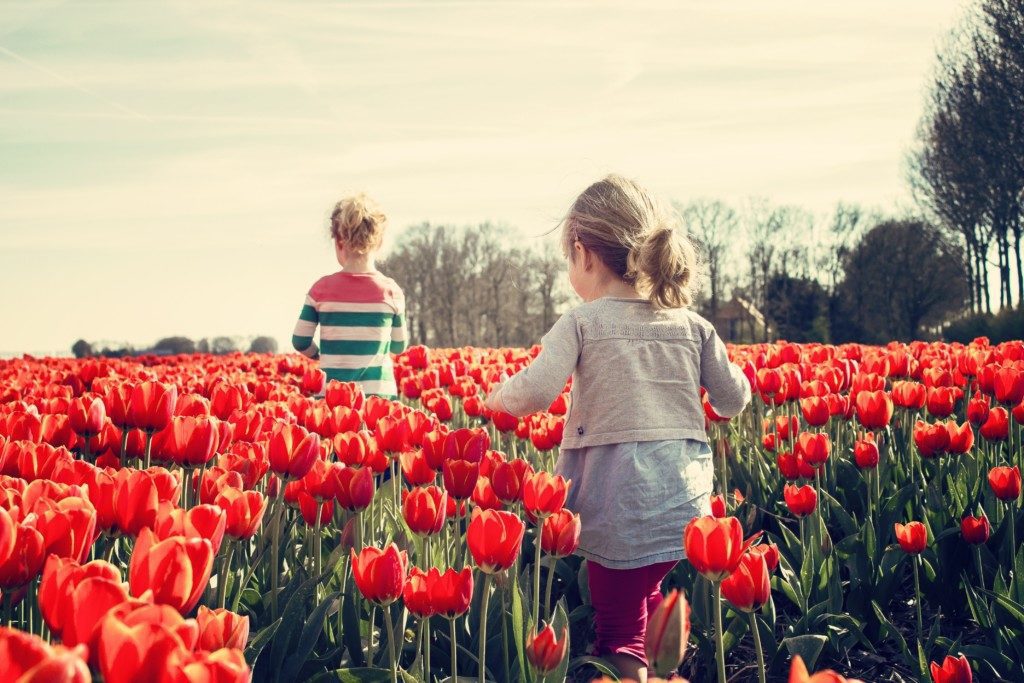 girls walking through field of tulips Providence Moms Blog Springtime