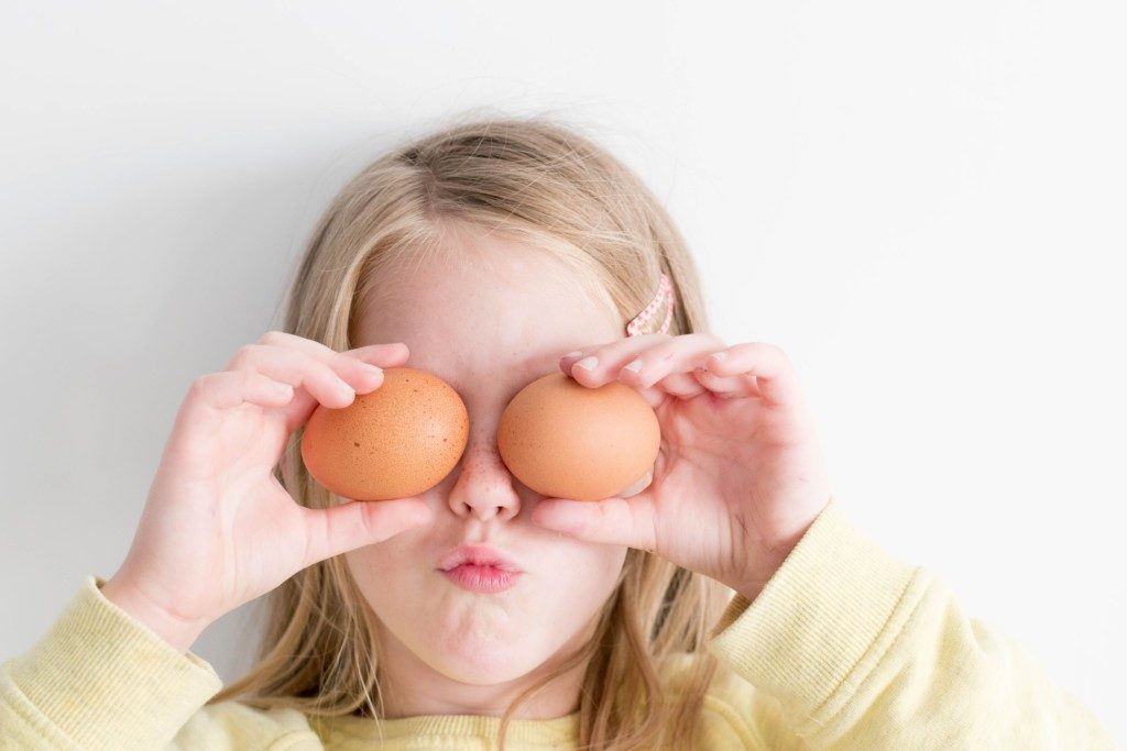 girl holding eggs over her eyes Providence Moms Blog