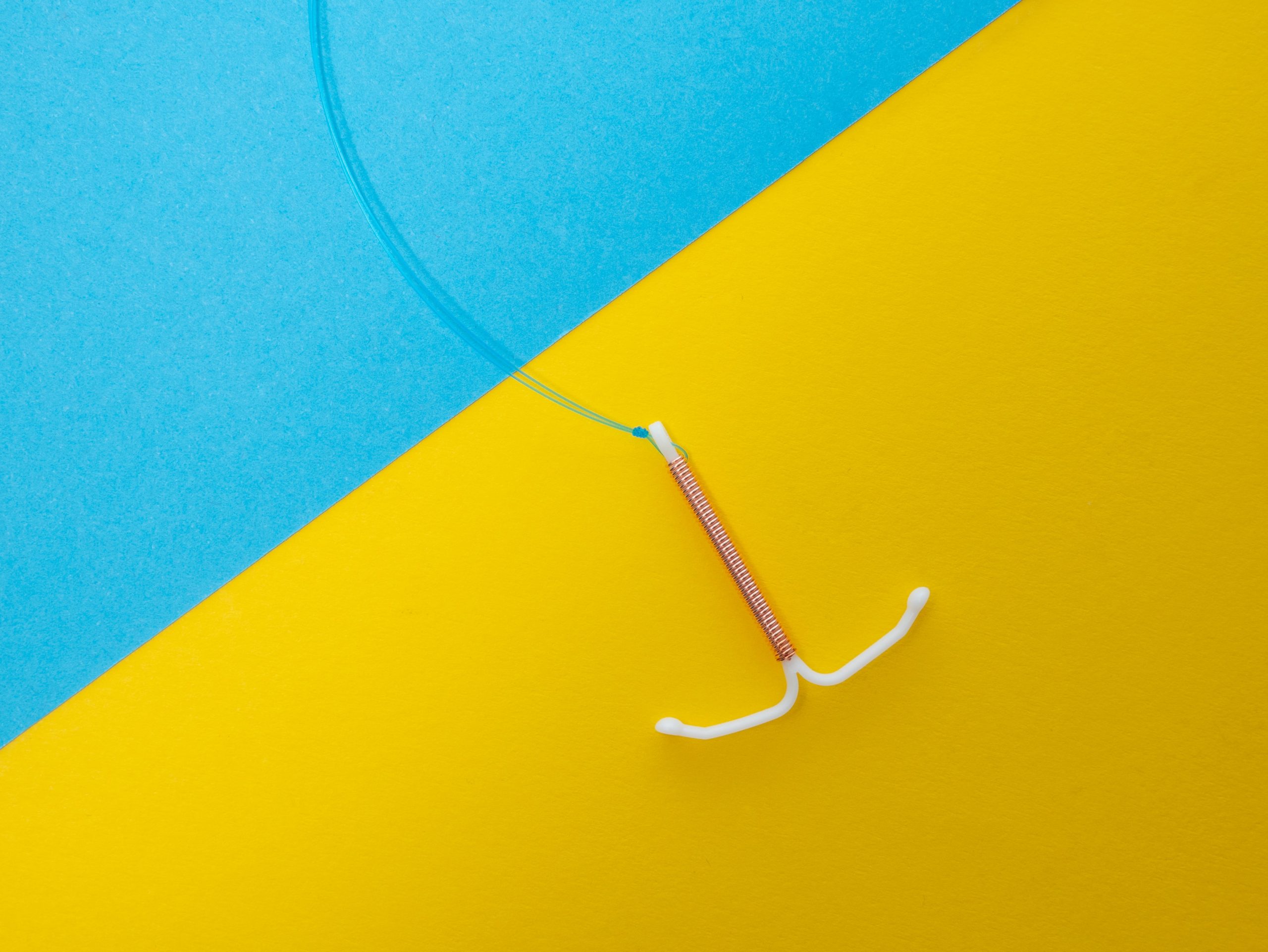And IUD on on a blue and yellow background to illustrate IUD failure 