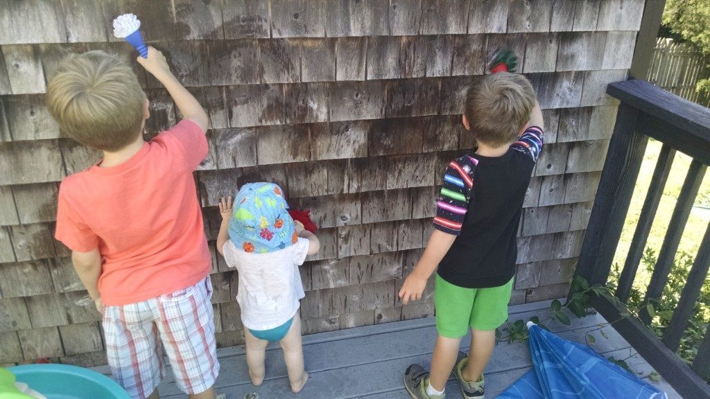 three children painting with water on exterior of house Providence Moms Blog