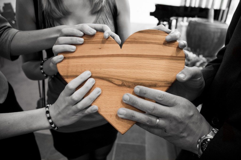 group of adults holding a wooden heart Providence Moms Blog