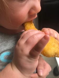 Young toddler Eating a chicken finger from Dunkin' Run menu. 
