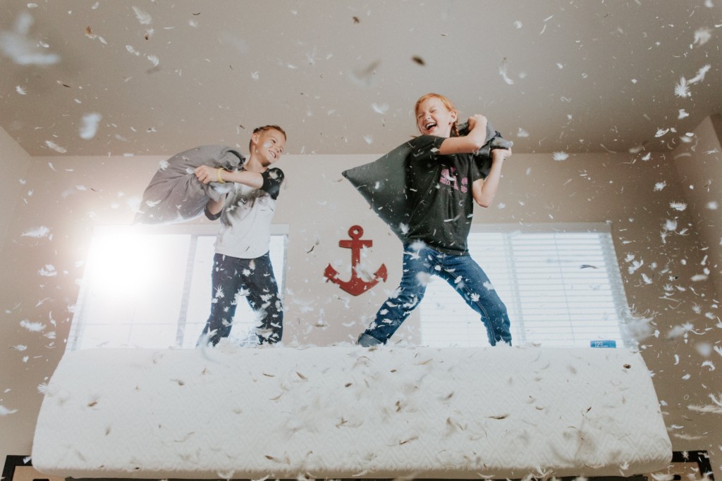 two boys having a pillow fight on a mattress Providence Moms Blog