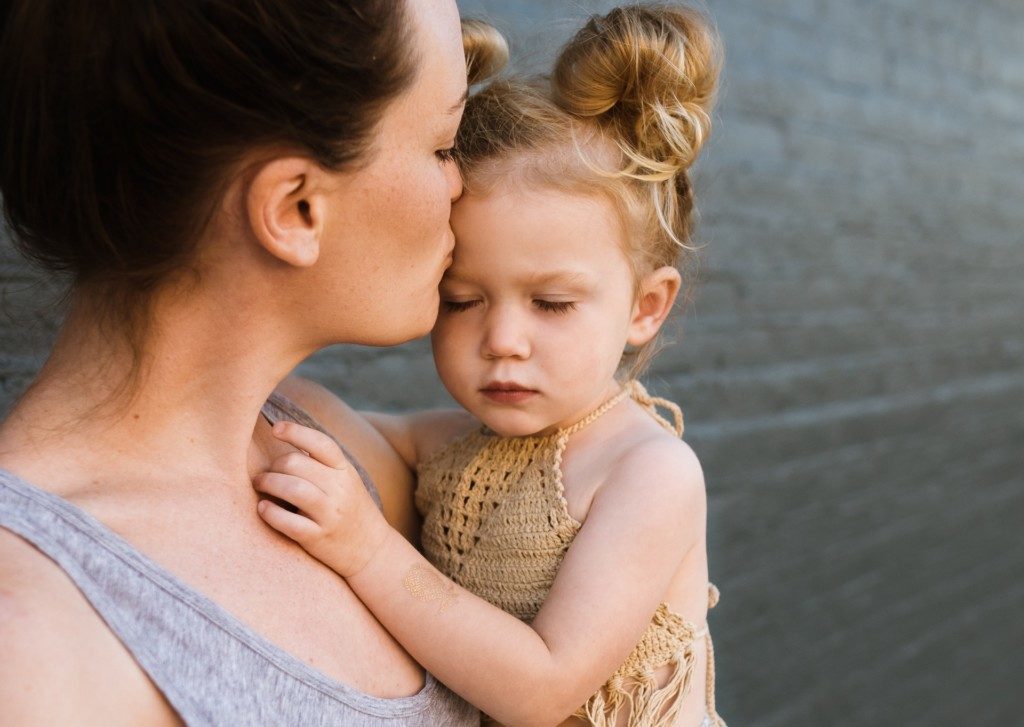 mother kissing daughter's forehead Providence Moms Blog