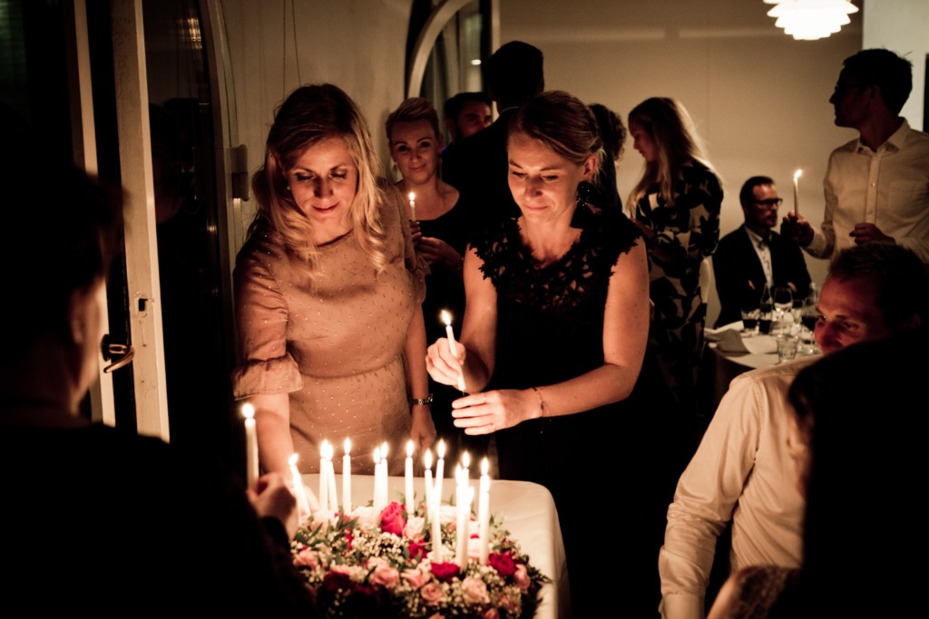 Two women standing by a birthday cake with lit candles. Image in Providence Moms Blog post on life lessons