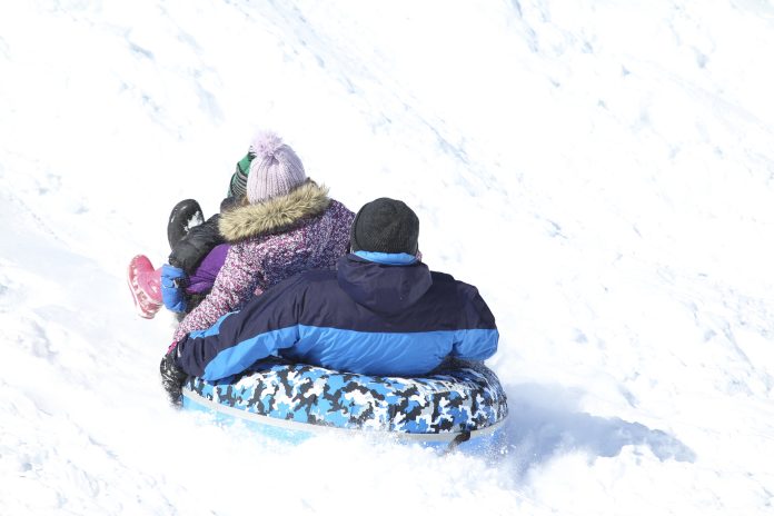 Father and daughters playing in snow sledding, New England, US