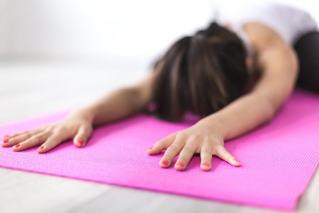 white woman doing yoga on a pink yoga mat