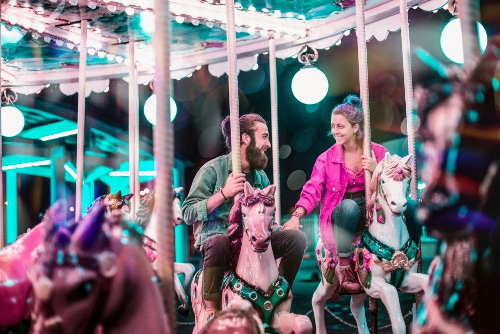 man with beard and woman wearing pink riding carousel 