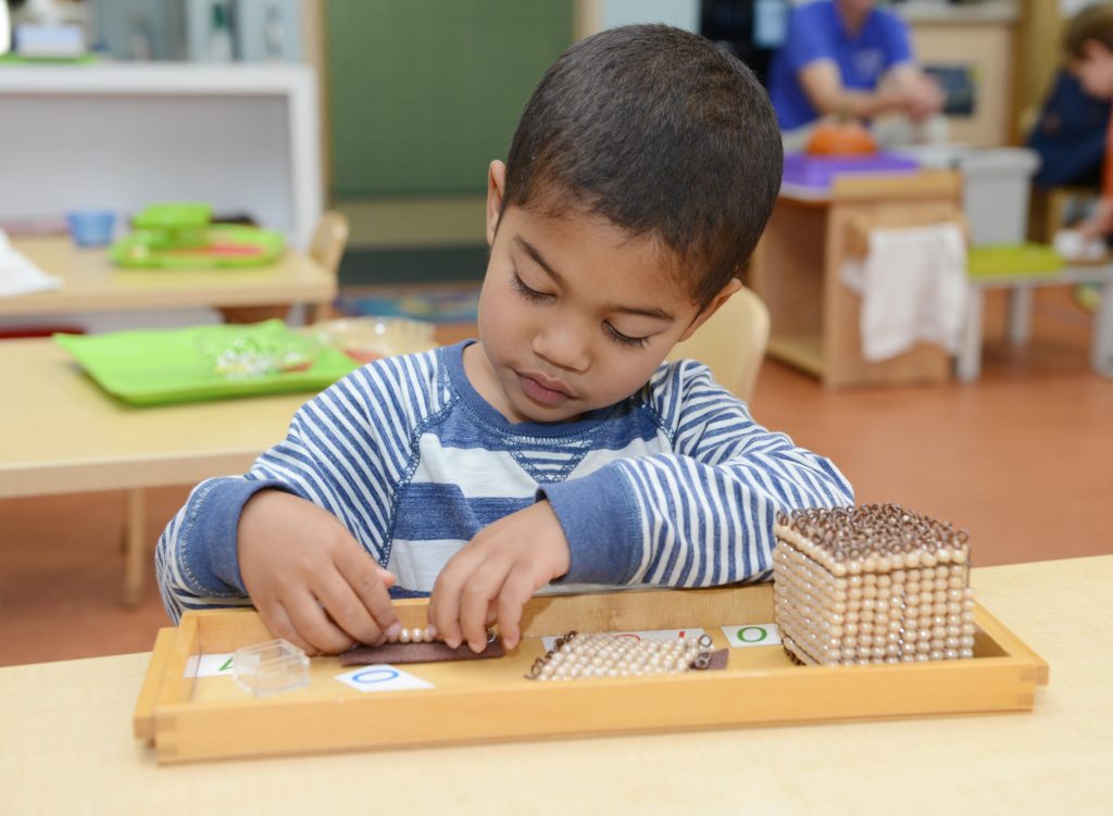 young boy working on math skills at Ocean State Montessori School