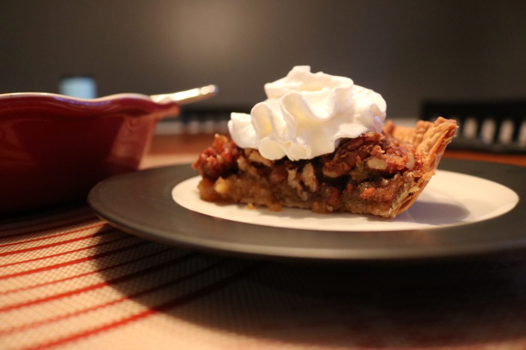 A slice of pecan pie served with whipped cream