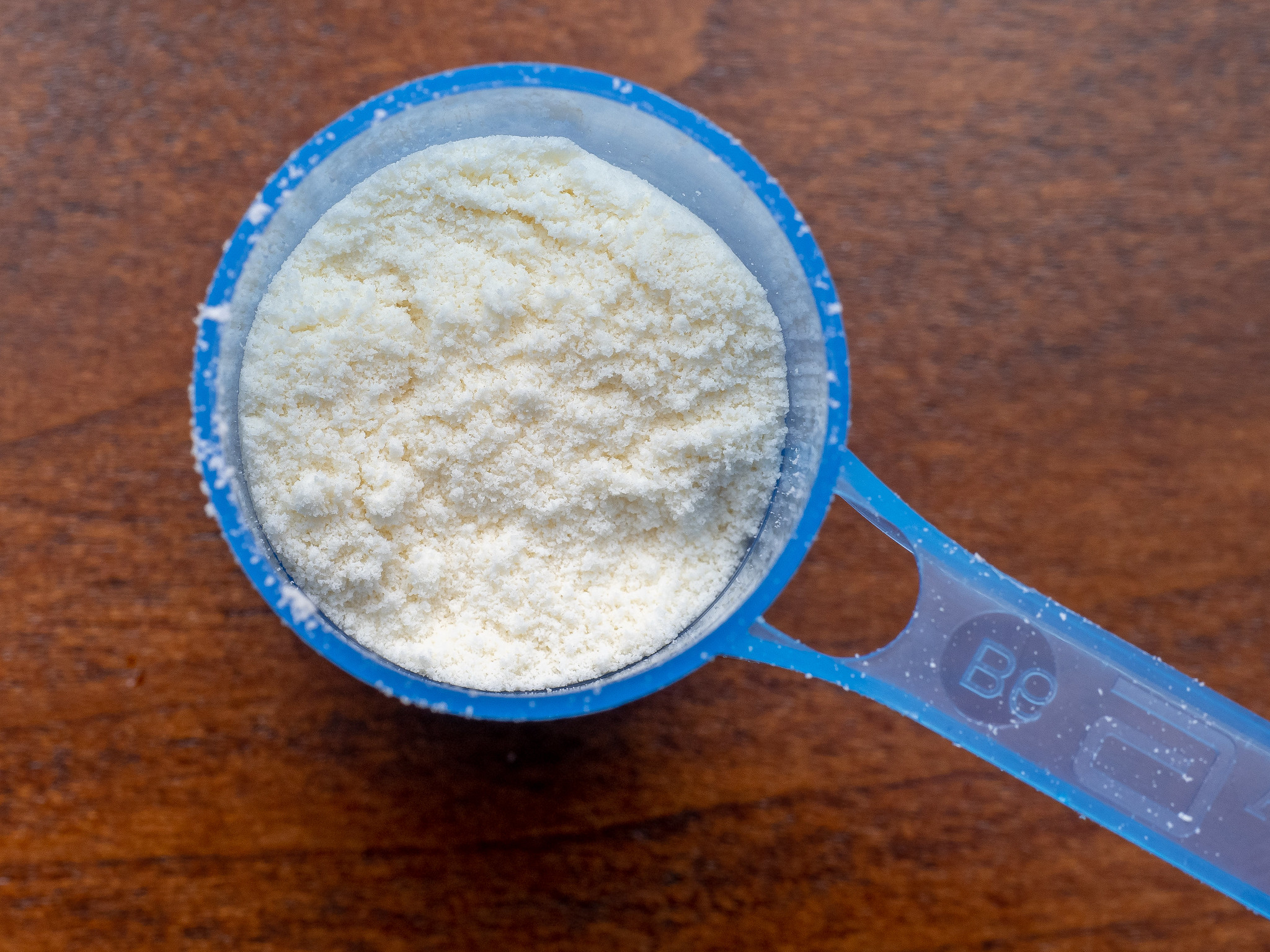 A measuring cup full of powdered baby formula