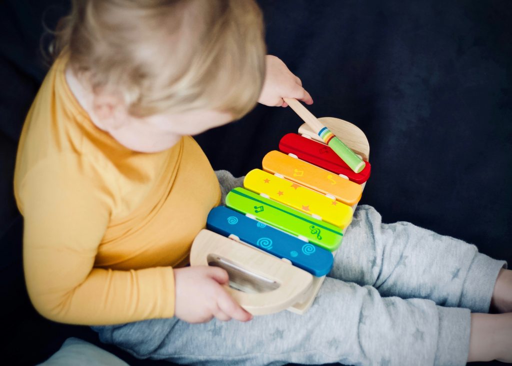 toddler playing with toy xylophone