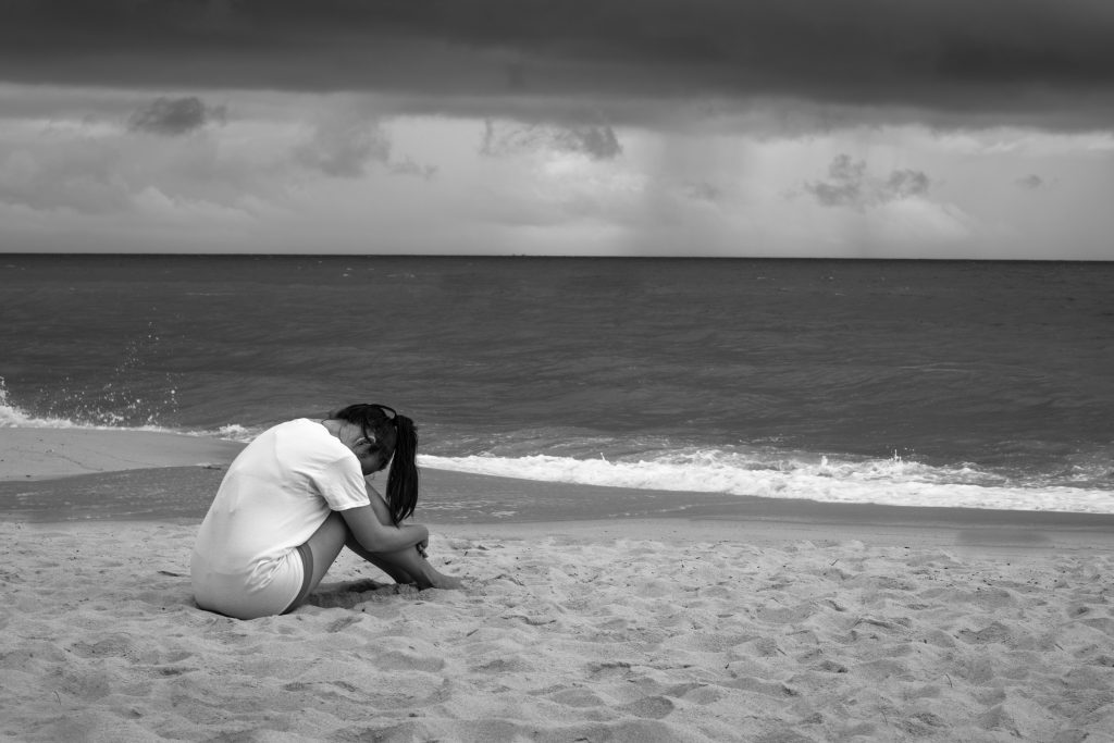 Sad woman or bereaved mother alone in front of the ocean